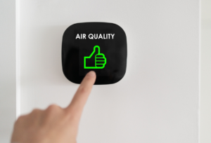 Hand touching a black smart button displaying AIR QUALITY text with a bright green thumbs up icon.