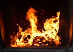 Close-up view of intense orange and yellow flames burning inside a furnace chamber with dark background.
